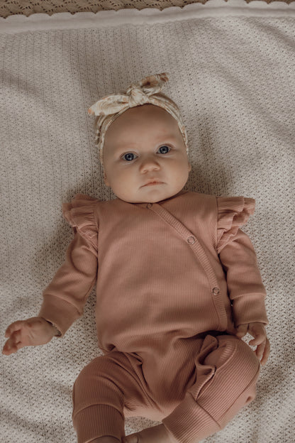 Boxpakje voor meisjes gemaakt van blush roze ribstof met een dubbel ruffletje op de schouder