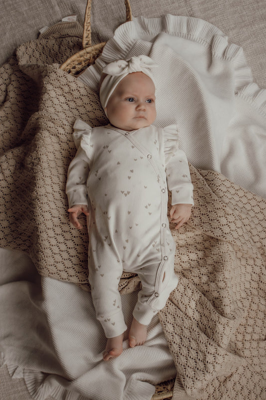 Meisjes boxpakje in de kleur wit met beige hartjesprint en ruffles op de schouder